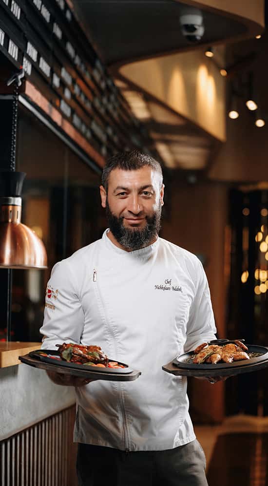 A head chef with two dishes in the restaurant hall