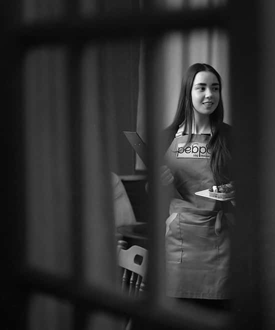 A waitress in an apron with the Rebro logo, black and white photo