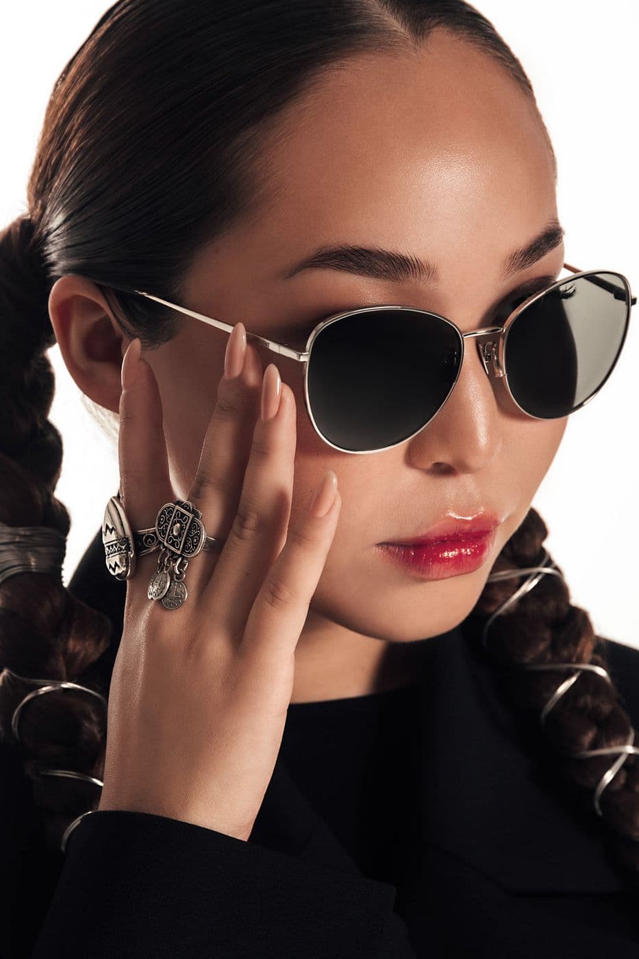 A close-up of a girl in sunglasses with a metal frame, hand near the face
