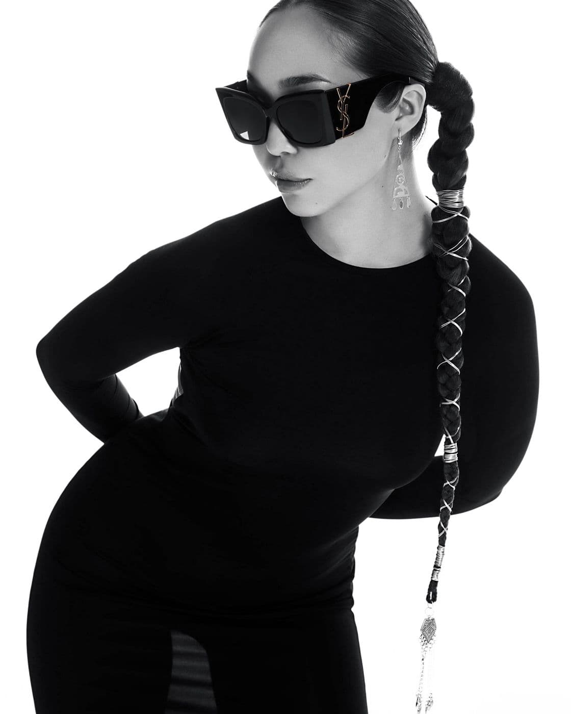 A black and white portrait of a girl in dark glasses with long braids