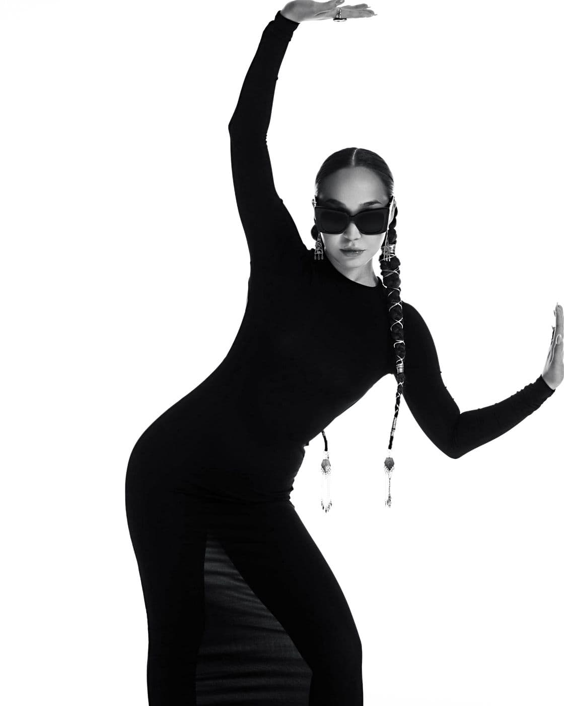 A black and white studio shot: a girl in glasses in a dynamic pose