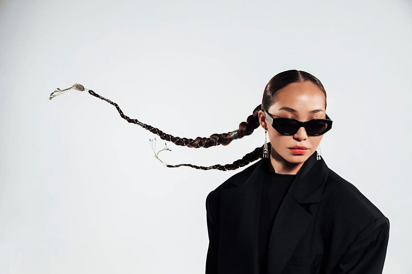 A girl in glasses with flying braids on a light background