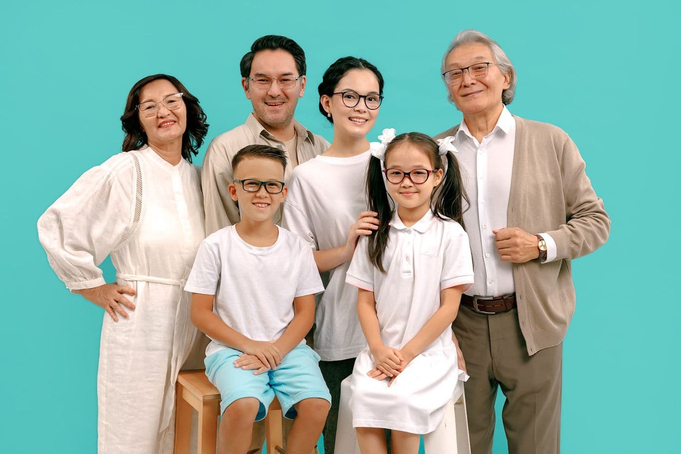 A family portrait of three generations in glasses on a turquoise background