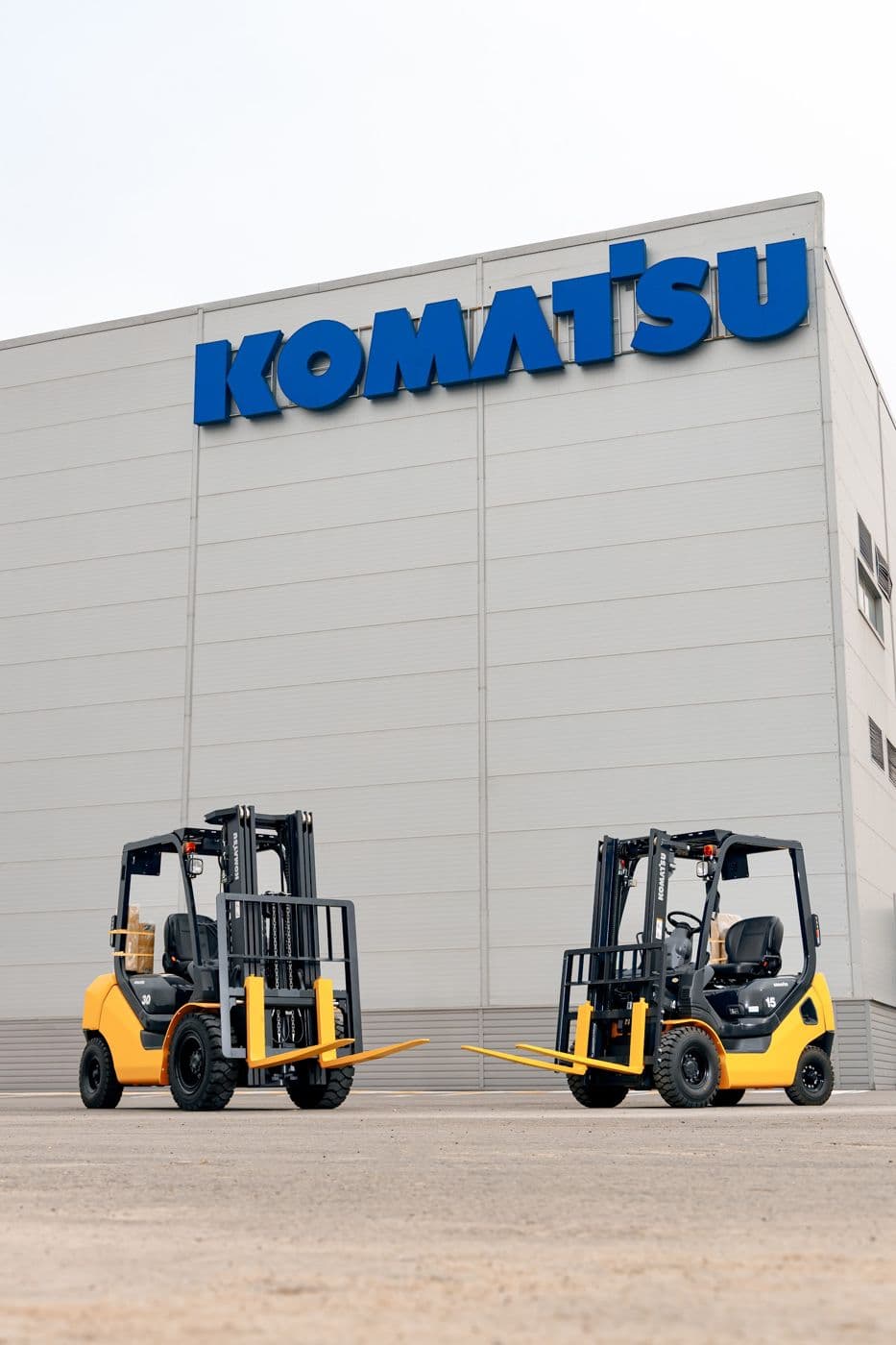 Два погрузчика Komatsu стоят рядом на площадке у склада