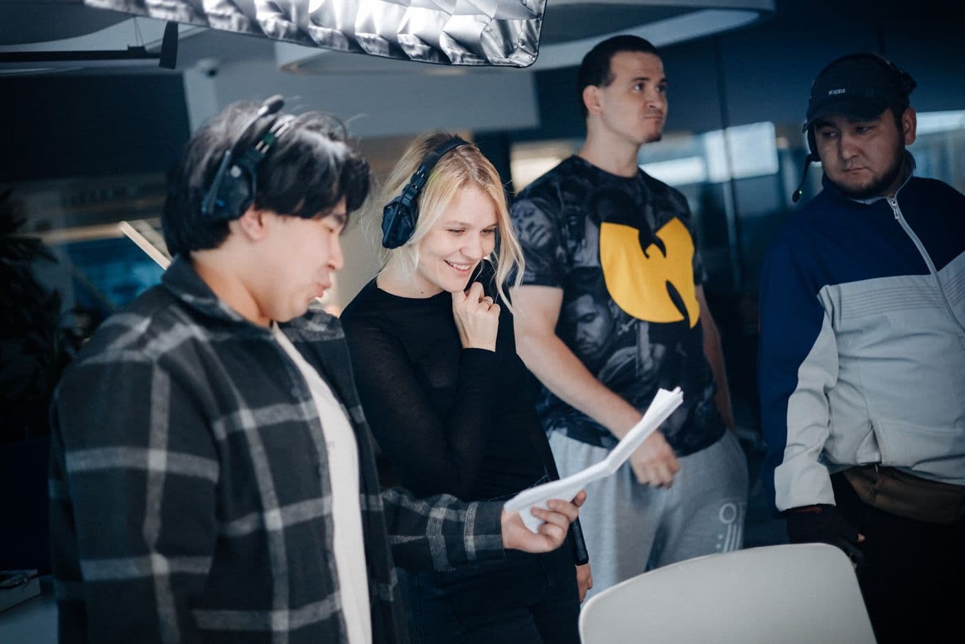 Құлаққап киген түсірілім тобының төрт мүшесі көріністің парақтарын қарап тұр