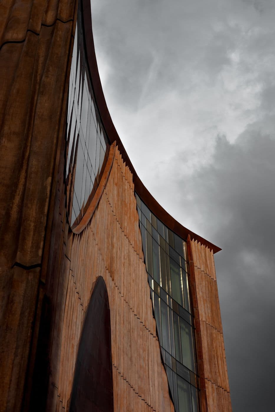 The façade of The Veil: a curved line of wood and glass against clouds
