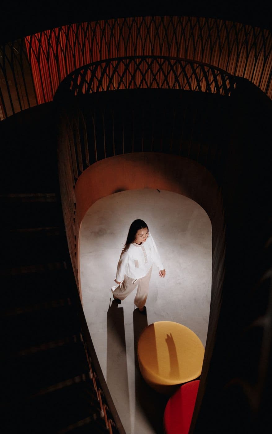 A girl in white descending a spiral staircase, view from above