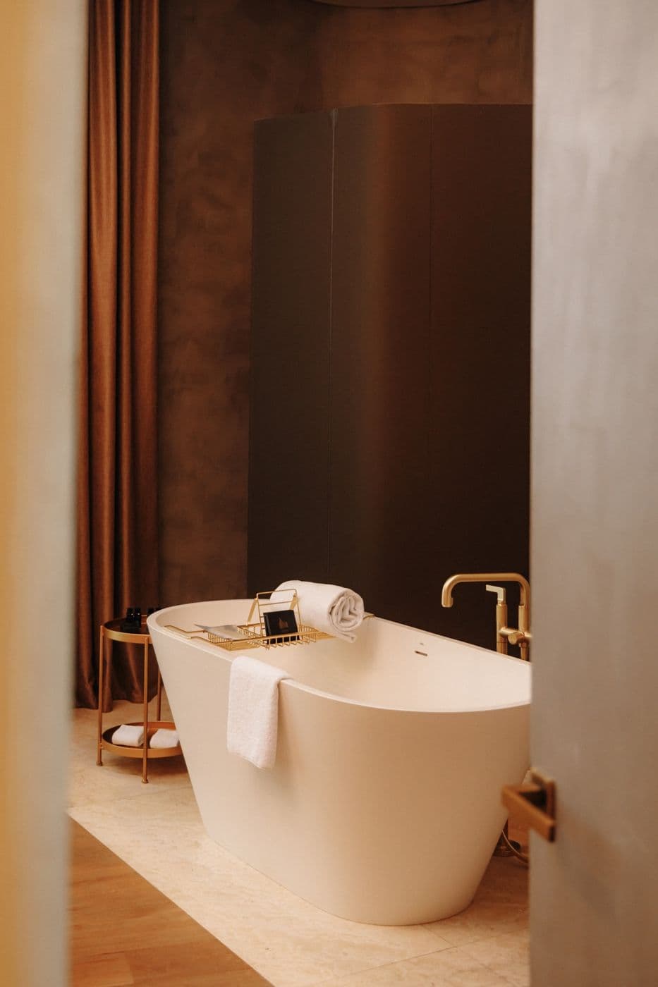 A freestanding bathtub and wooden finishing in a hotel room